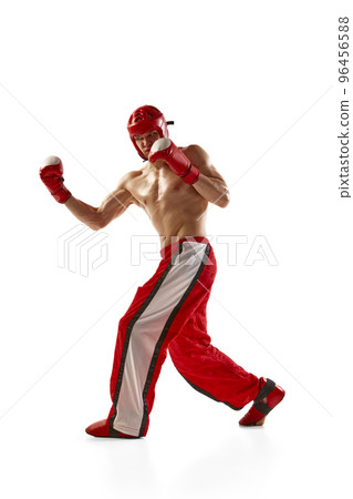 Punch. Young muscled athlete, professional kickboxer in protective helmet and boxing gloves in action isolated on white background. Sport, competition, energy, combat sports 96456588