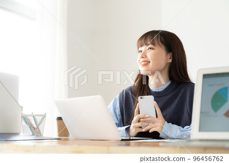 Young woman operating a smartphone in the office 96456762