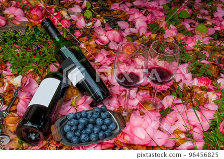 bottles, wine glasses with blueberry in rose garden. 96456825