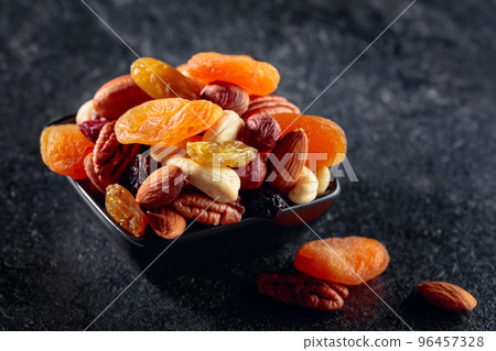 Dried fruits and nuts on a black stone table. Dried fruits and nuts on a black stone table. 96457328