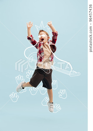 Creative design with drawn elements. Portrait of cheerful little boy, child having fun with music. Future guitar player and singer 96457436