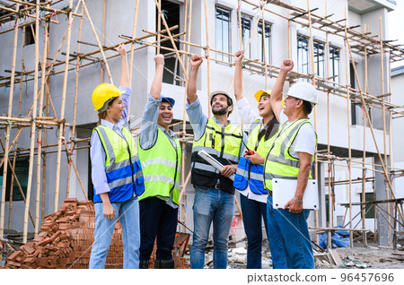 Group of contractors, engineers and formats in safety vests with helmets hands up to work together to successfully complete a construction project on construction site. cooperation and success 96457696