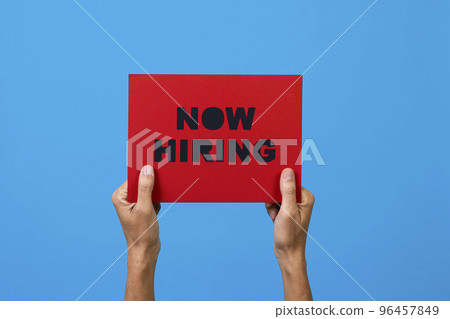 holds a sign with the text now hiring holds a sign with the text now hiring 96457849