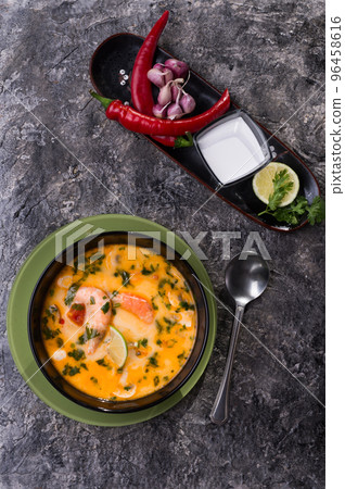famous delicious Thai Tom yum spicy soup with shrimps and coconut milk on black table. flat lay famous delicious Thai Tom yum spicy soup with shrimps and coconut milk on black table. flat lay 96458616
