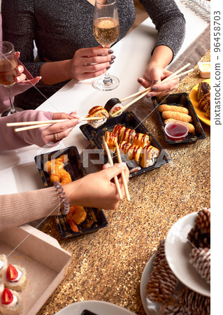 Portrait of three beautiful young women eating japanese food and drinking wine at home. Portrait of three beautiful young women eating japanese food and drinking wine at home. 96458703