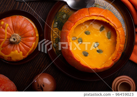 baked pumpkin cream coup served in pumpkin with corn. served at wooden brown table with ripe orange pumkins. flat lay. healthy life concept baked pumpkin cream coup served in pumpkin with corn. served at wooden brown table with ripe orange pumkins. flat lay. healthy life concept 96459023