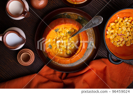 baked pumpkin cream coup served in pumpkin with corn. served at wooden brown table with ripe orange pumkins. flat lay. healthy life concept baked pumpkin cream coup served in pumpkin with corn. served at wooden brown table with ripe orange pumkins. flat lay. healthy life concept 96459024