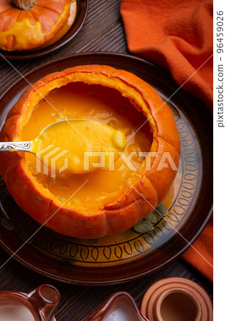 baked pumpkin cream coup served in pumpkin with corn. served at wooden brown table with ripe orange pumkins. flat lay. healthy life concept. close up baked pumpkin cream coup served in pumpkin with corn. served at wooden brown table with ripe orange pumkins. flat lay. healthy life concept. close up 96459026