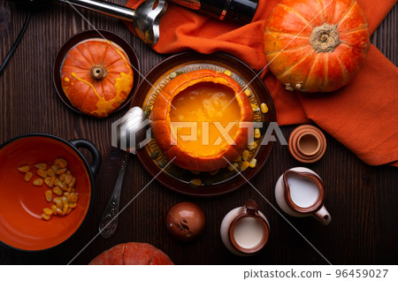 baked pumpkin cream coup served in pumpkin with corn. served at wooden brown table with ripe orange pumkins. flat lay. healthy life concept baked pumpkin cream coup served in pumpkin with corn. served at wooden brown table with ripe orange pumkins. flat lay. healthy life concept 96459027