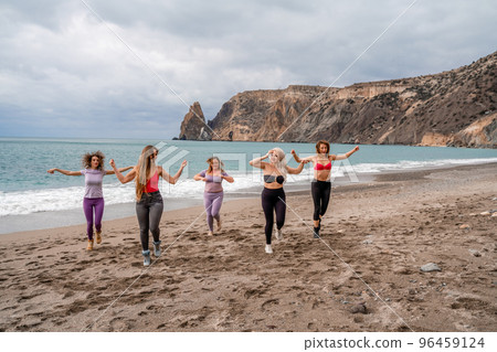A group of five female friends are doing exercises on the beach. Beach holiday concept, healthy lifestyle 96459124
