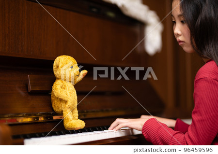 Teddy bear teaching a girl to play the piano Teddy bear teaching a girl to play the piano 96459596
