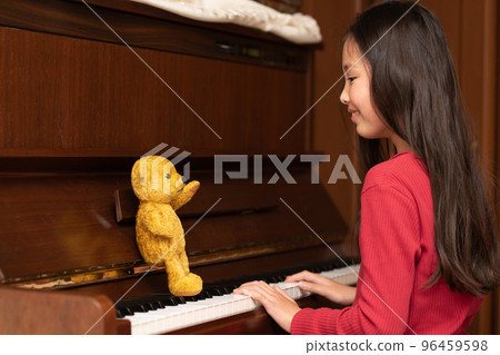 Teddy bear teaching a girl to play the piano Teddy bear teaching a girl to play the piano 96459598