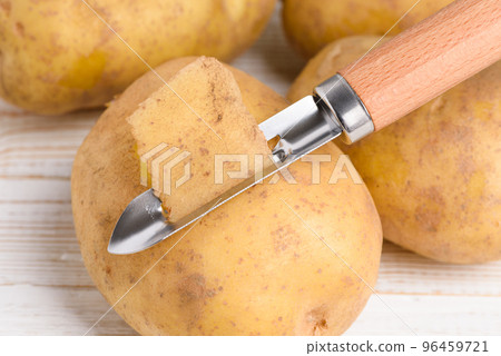 Raw potato peeled with vegetable peeler on white wooden table Raw potato peeled with vegetable peeler on white wooden table 96459721