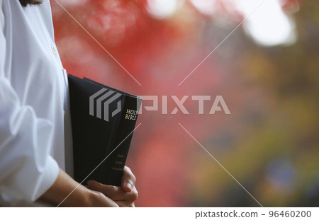 基督徒拿著聖經在街上宣講耶穌基督的福音和紅秋葉 96460200