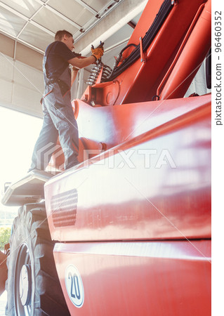 Machinist repairing a huge farm machine in his garage Machinist repairing a huge farm machine in his garage 96460352
