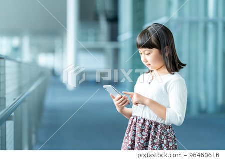 Elementary school girl using a smartphone Elementary school girl using a smartphone 96460616