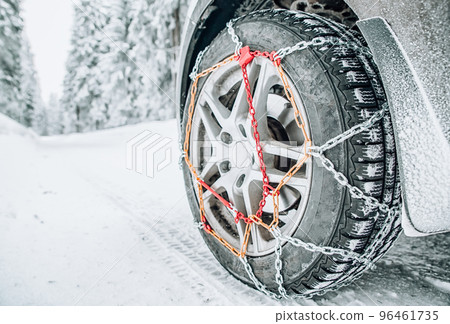 Snow chains on tire of car on snowy road in winter 96461735