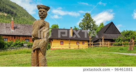 Wooden statue of villager in front of picturesque historical village Vlkolinec witjh wooden colorful cottages in Slovakia 96461881