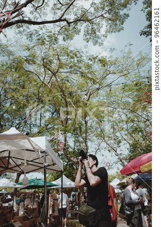 Young man traveller touring in street market and using his camera for take a photo Young man traveller touring in street market and using his camera for take a photo 96462161