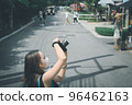 Young woman traveller using camera when her tour a street market 96462163