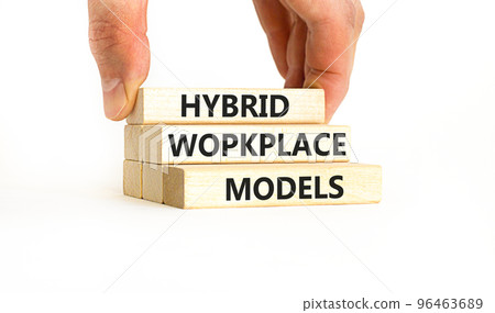 Hybrid workplace models symbol. Concept words Hybrid workplace models on wooden blocks. Businessman hand. Beautiful white background. Business hybrid workplace models quote concept. Copy space Hybrid workplace models symbol. Concept words Hybrid workplace models on wooden blocks. Businessman hand. Beautiful white background. Business hybrid workplace models quote concept. Copy space 96463689