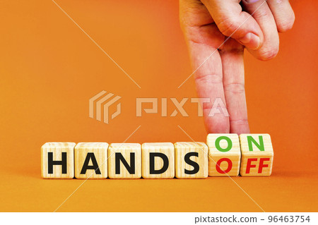 Hands on or off symbol. Concept words Hands on Hands off on wooden cubes. Businessman hand. Beautiful orange table orange background. Business hands on or off concept. Copy space. Hands on or off symbol. Concept words Hands on Hands off on wooden cubes. Businessman hand. Beautiful orange table orange background. Business hands on or off concept. Copy space. 96463754