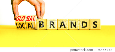 Global or local brands symbol. Concept words Global brands and Local brands on wooden cubes. Businessman hand. Beautiful yellow table white background. Business global local brand concept. Copy space. 96463758