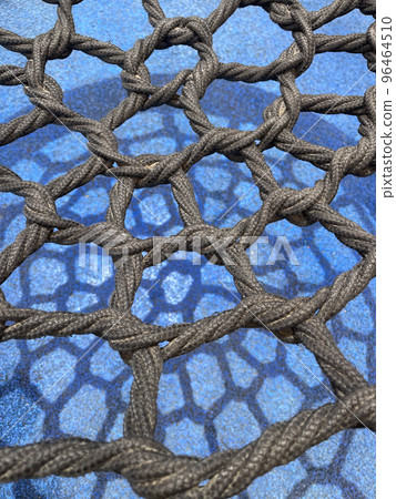 Black thick woven mesh on the blue background with a shadow from it. Black thick woven mesh on the blue background with a shadow from it. 96464510