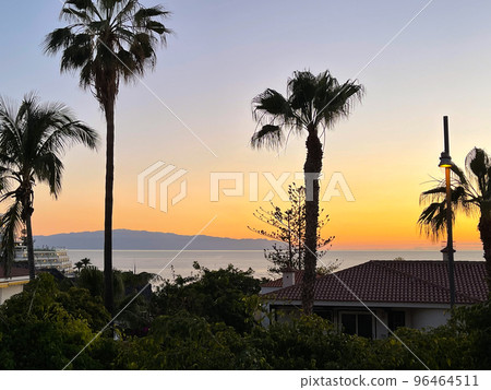 View to the island in the ocean through palm trees. Sunset on the island. View to the island in the ocean through palm trees. Sunset on the island. 96464511