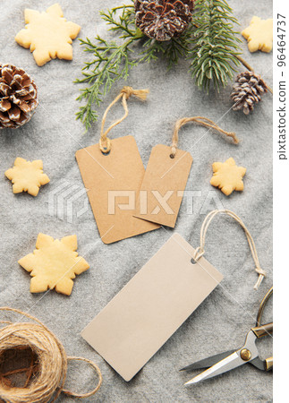 Blank gift tags with pine branch and Christmas cookies on textile background. The concept of preparing for the Christmas holiday Blank gift tags with pine branch and Christmas cookies on textile background. The concept of preparing for the Christmas holiday 96464737