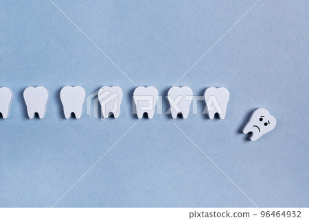 Teeth row with fallen baby milk or sick adult one with sad emoji on blue background. Tooth loss caused by no professional dental care, poor oral hygiene, gums diseases, trauma. Teeth row with fallen baby milk or sick adult one with sad emoji on blue background. Tooth loss caused by no professional dental care, poor oral hygiene, gums diseases, trauma. 96464932