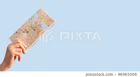Paper map, travel guide in hand on blue background 96465009
