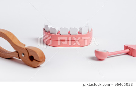 Wooden jaw model with dental forceps and mirror. Dentist instruments for teeth checkup and extraction. Children game at doctor Wooden jaw model with dental forceps and mirror. Dentist instruments for teeth checkup and extraction. Children game at doctor 96465038