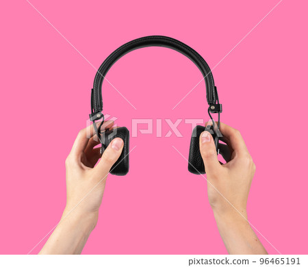 Hands holding wireless headphones on pink background. Audio concept. Accessories for leisure, study. Hands holding wireless headphones on pink background. Audio concept. Accessories for leisure, study. 96465191