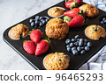 Assorted blueberry and strawberry muffins in a baking tin. Close up. 96465293
