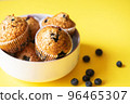 Blueberry muffins served on a white bowl on a yellow background. Close up. 96465307