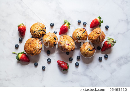 Blueberry and strawberry muffins on a white marble background. 96465310