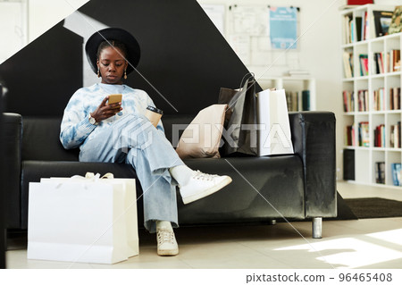 Young black woman relaxing at thrift store 96465408
