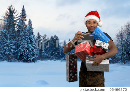 man holding gift boxes for christmas in the snow winter landscape and wearing red santa hat outside man holding gift boxes for christmas in the snow winter landscape and wearing red santa hat outside 96466270