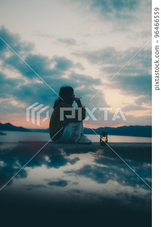 Silhouette photo of a young woman sitting and blowing bubbles Silhouette photo of a young woman sitting and blowing bubbles 96466559