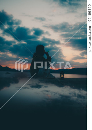 Silhouette photo of a young woman sitting and blowing bubbles 96466560