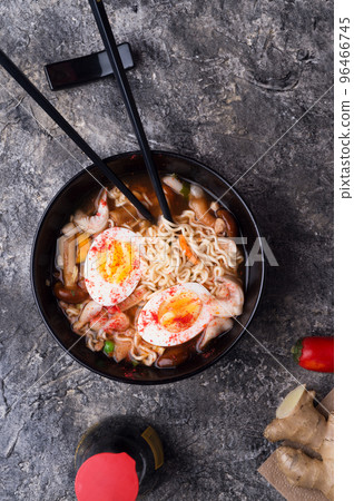spicy instant noodles soup with shrimps, egg and  mushrooms. served  by black chopsticks. flat lay 96466745