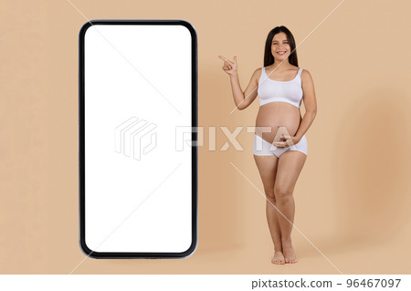 Mobile Offer. Smiling Pregnant Woman Pointing Aside At Big Blank Smartphone 96467097