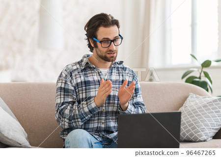 Serious busy young european man with stubble in glasses has video call, meeting on computer 96467265