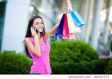 Woman walk near shopping mall with colored packs Woman walk near shopping mall with colored packs 96467571