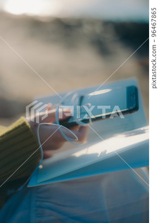 Photo of a young woman standing while reading a book on the riverbed 96467865