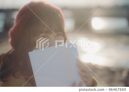 Photo of a young woman standing while reading a book on the riverbed 96467889