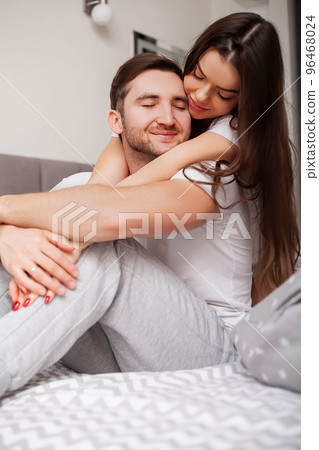 Happy sensual young couple lying in bed together Happy sensual young couple lying in bed together 96468024