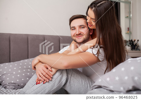 Happy sensual young couple lying in bed together 96468025