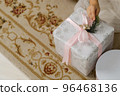 Little hand holding pink ribbon on a Christmas present wrapped in beautiful white paper 96468136